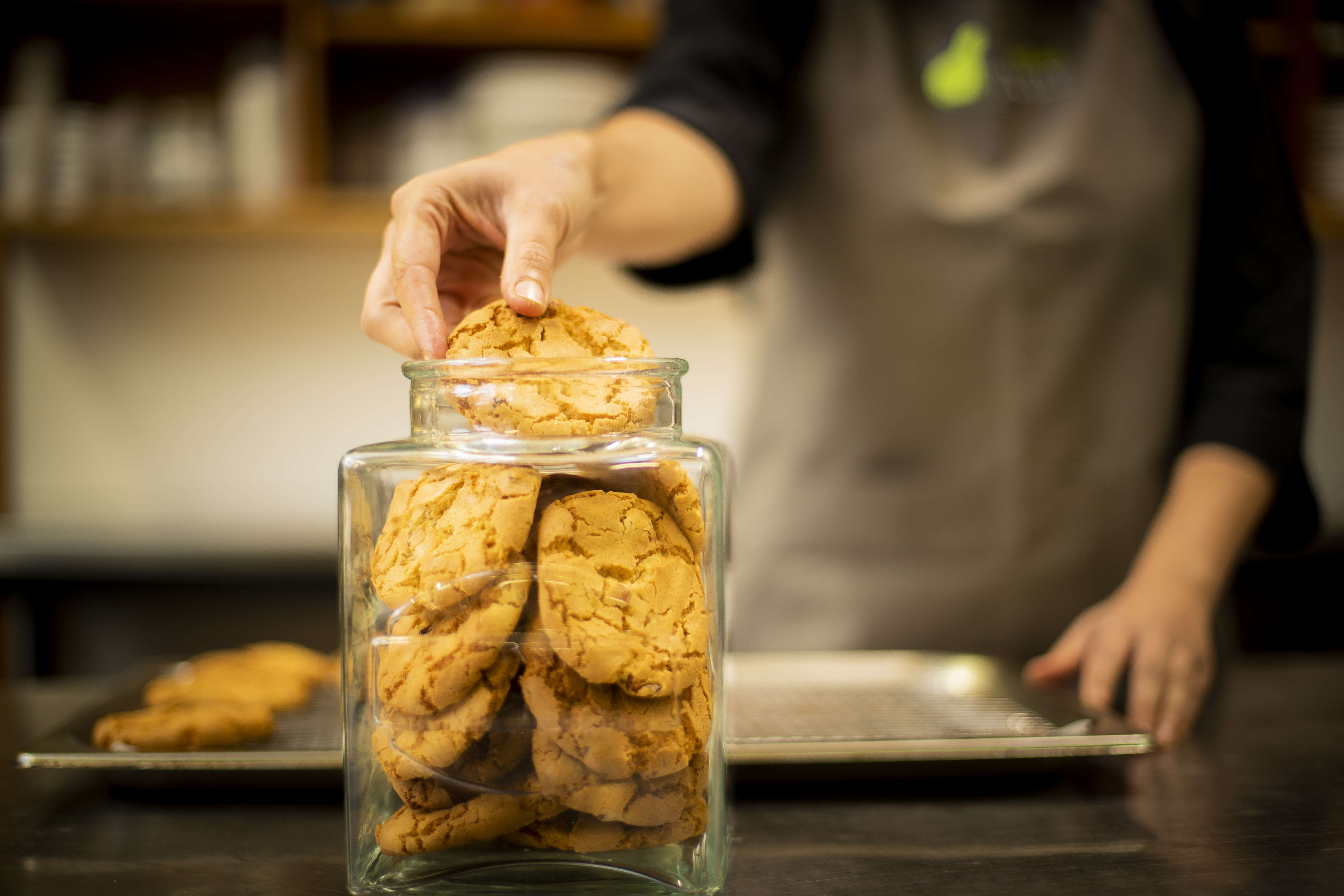 Close up of chef placing cookies into a glass jar. Photo: Richard Jupe.