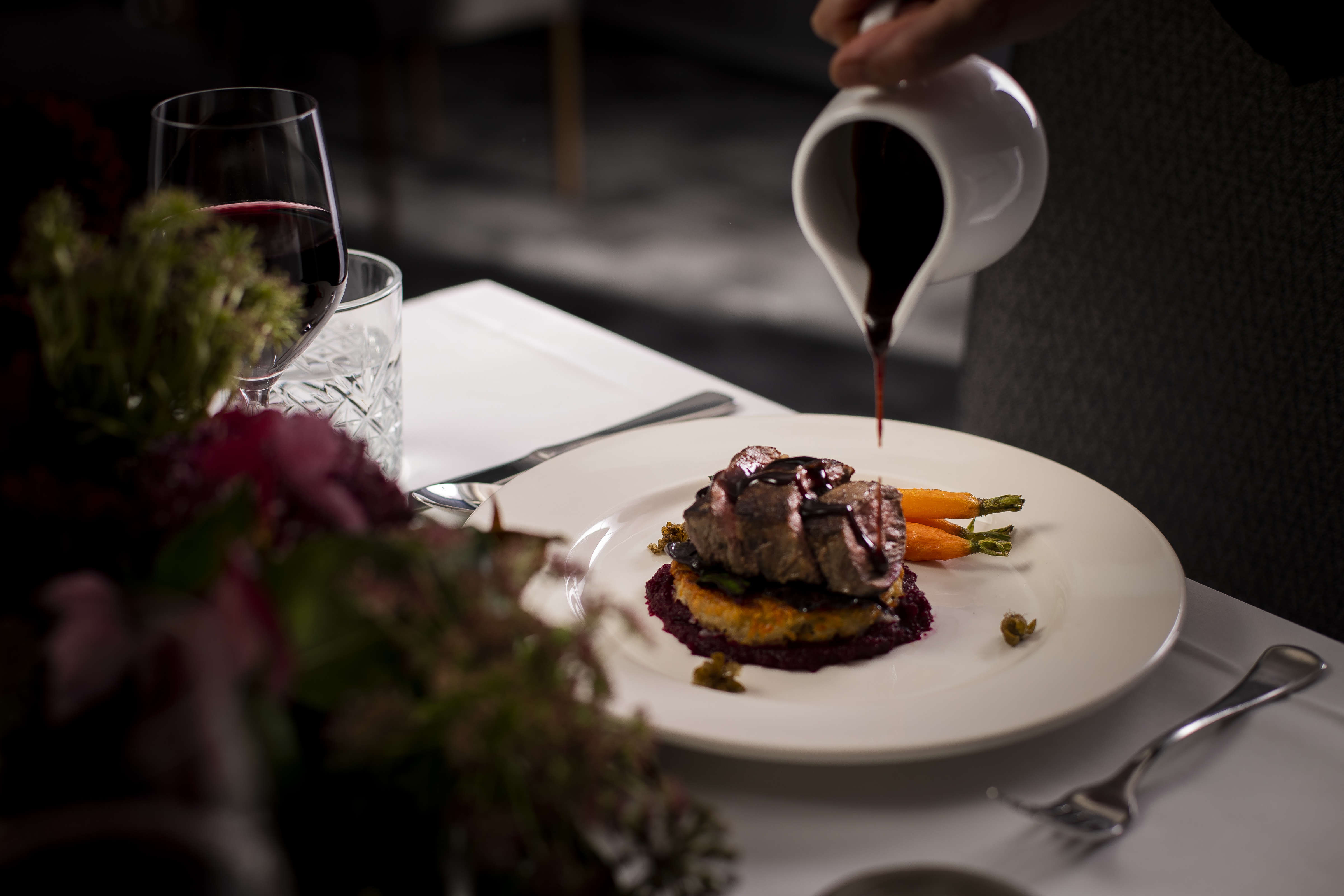 Roasted eye fillet slices on hashbrown with beetroot puree and roast baby carrots glazed with jus on a white dinner plate. Photo: Richard Jupe.
