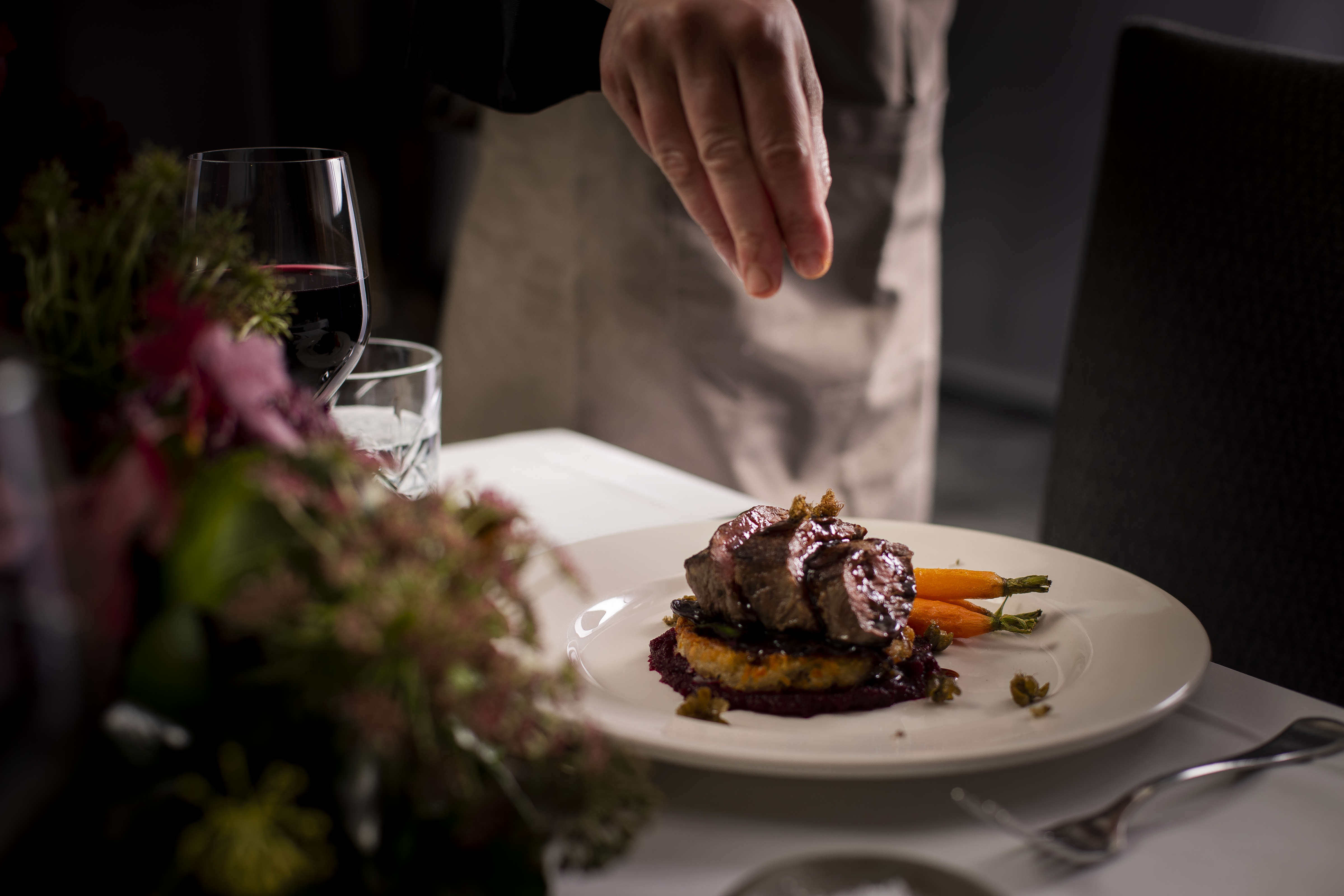 Roasted eye fillet slices on hashbrown with beetroot puree and roast baby carrots glazed with jus on a white dinner plate with fried capers being sprinkled on top. Photo: Richard Jupe.