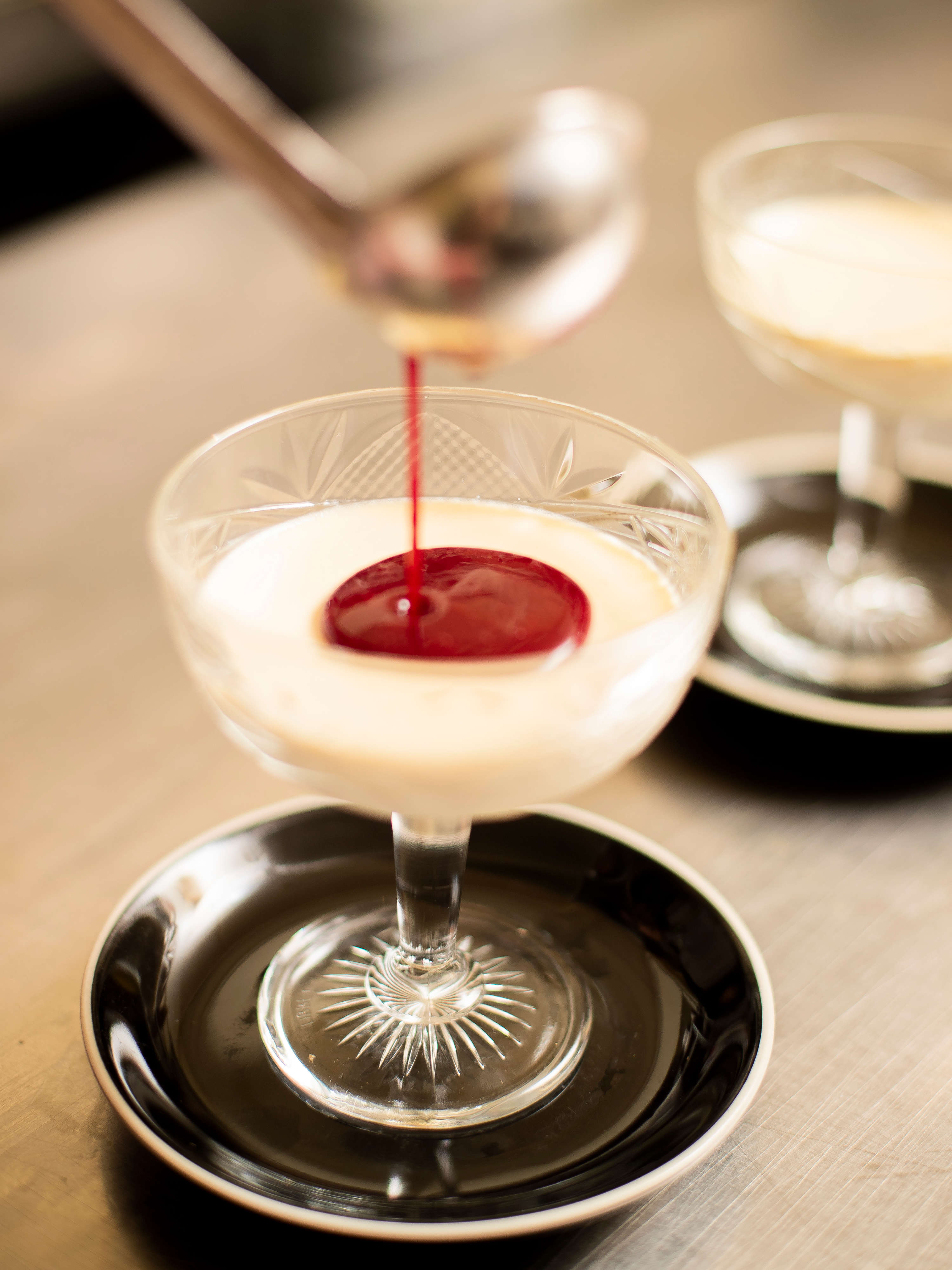 Vanilla panna cotta with raspberry coulis being drizzled on top. Photo: Richard Jupe.