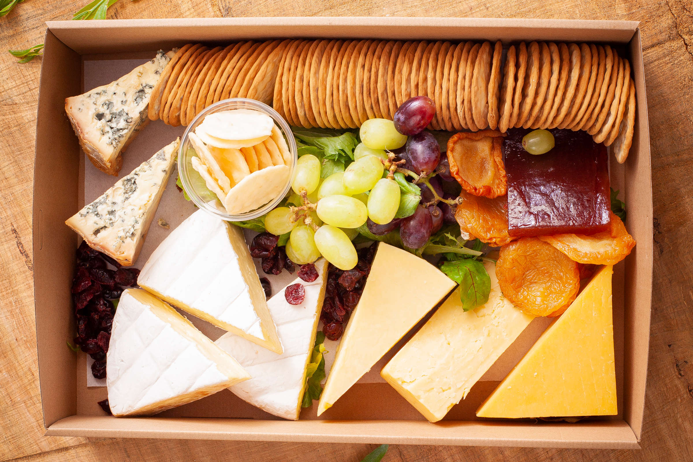 Close up of Tasmanian cheese and cracker box including brie, Mixed Ashgrove cheddar cheeses, Blue quince paste, dried pears, grapes and crackers. Credit: Richard Jupe.