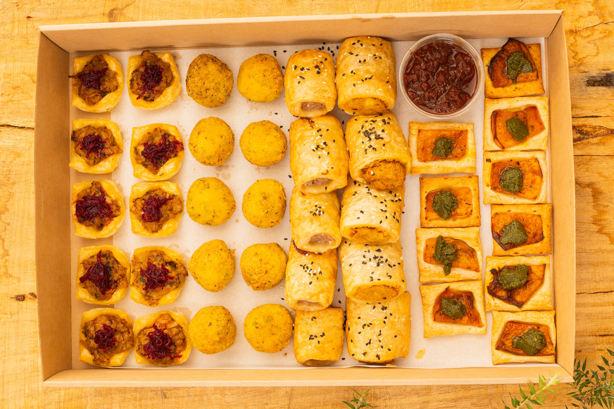 Hot gluten-free and vegan selection box containing 40 items, including savoury rolls, pea and basil arancini, pumpkin galette with salsa verde, and cauliflower pie. Credit: Richard Jupe.
